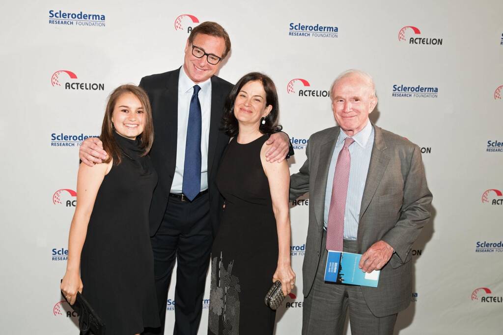 Four people standing together and smiling at a Scleroderma Research Foundation event, posing for a photograph in front of a branded backdrop.