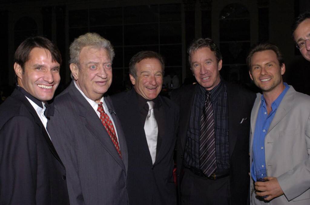 Five men in formal attire pose together, smiling at an indoor event.